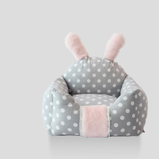 Children's bean bag chair with polka dot pattern and pink accents on a light gray background