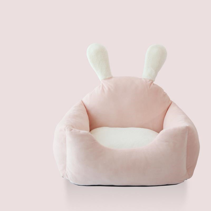 Pink children's bean bag chair with bunny ears on a light pink background