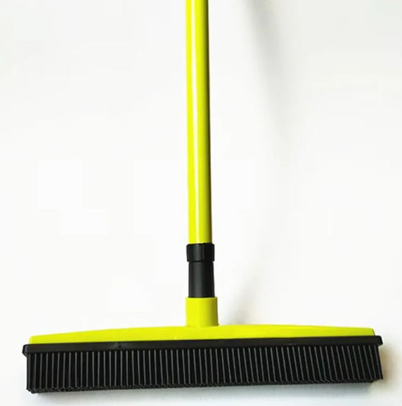 Yellow broom with black bristles on a white background