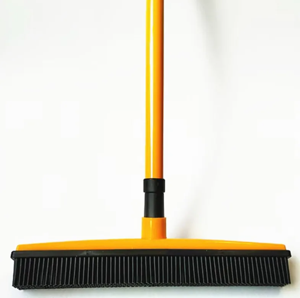 Yellow broom with black bristles on a white background