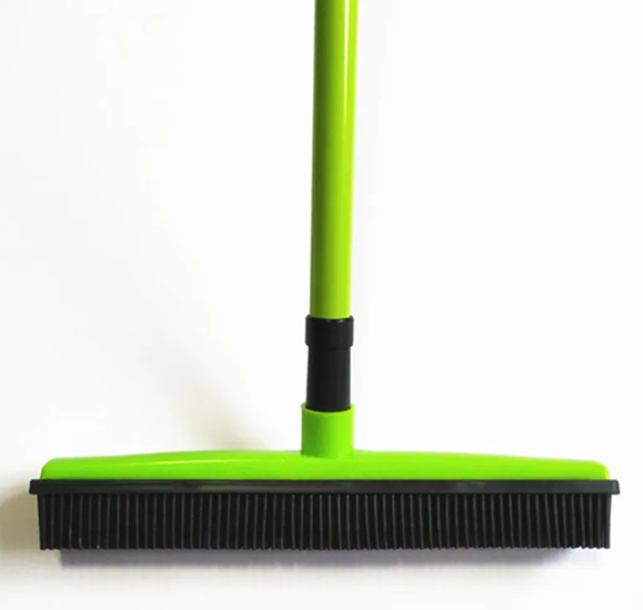 Green broom with black bristles on a white background